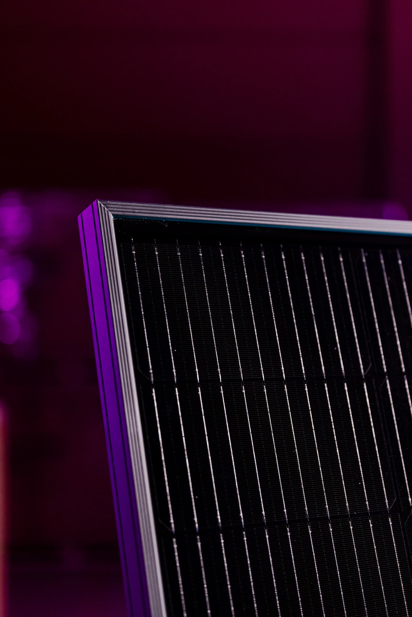 Lähikuva aurinkopaneelista, jonka pinta on tyylikkään musta, taustalla sumea violetti maisema.