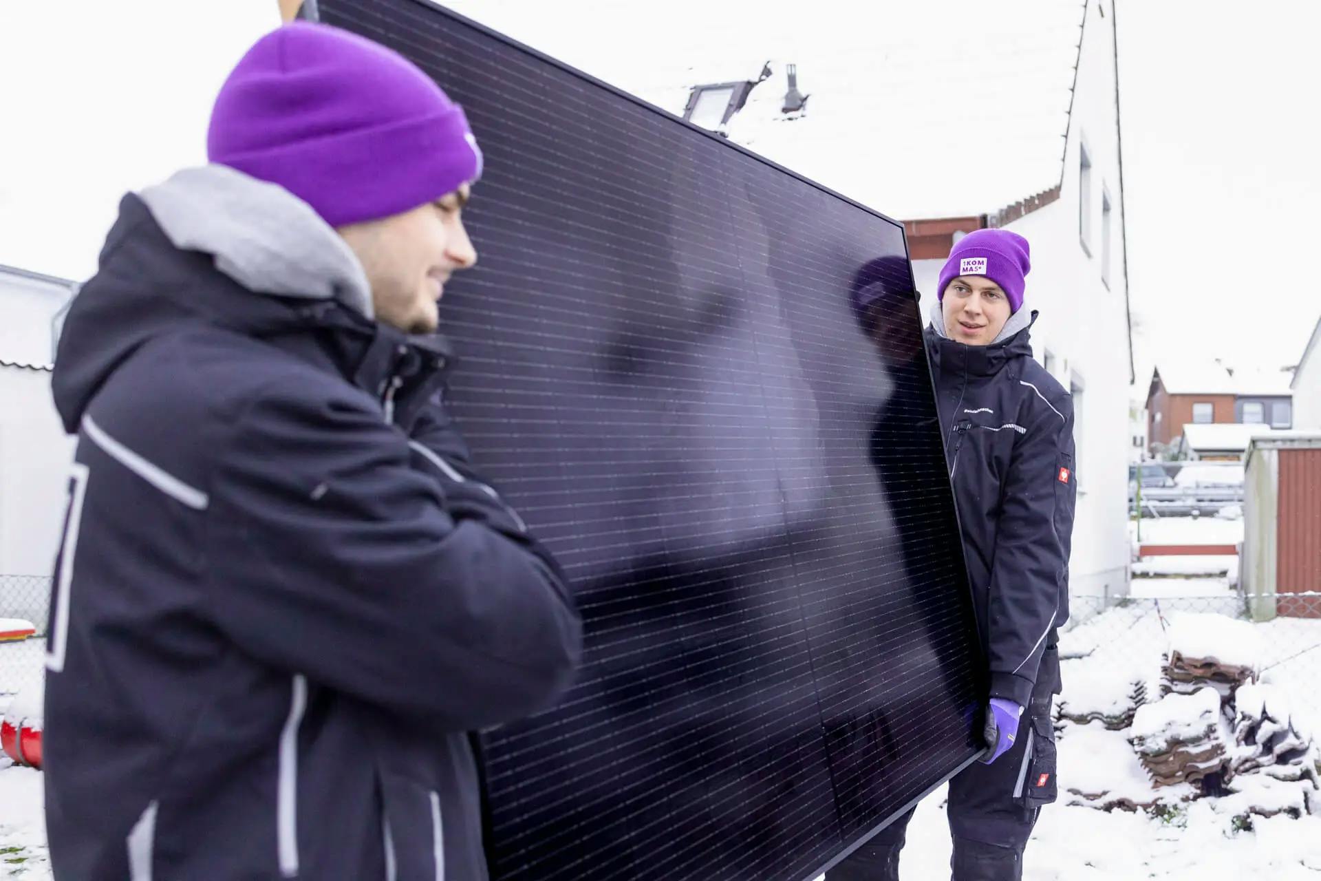Asentajat liikuttavat talvella aurinkopaneelia ulkona